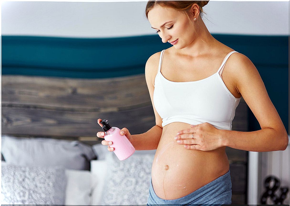 Pregnant woman applying moisturizer to reduce the appearance of stretch marks during pregnancy.