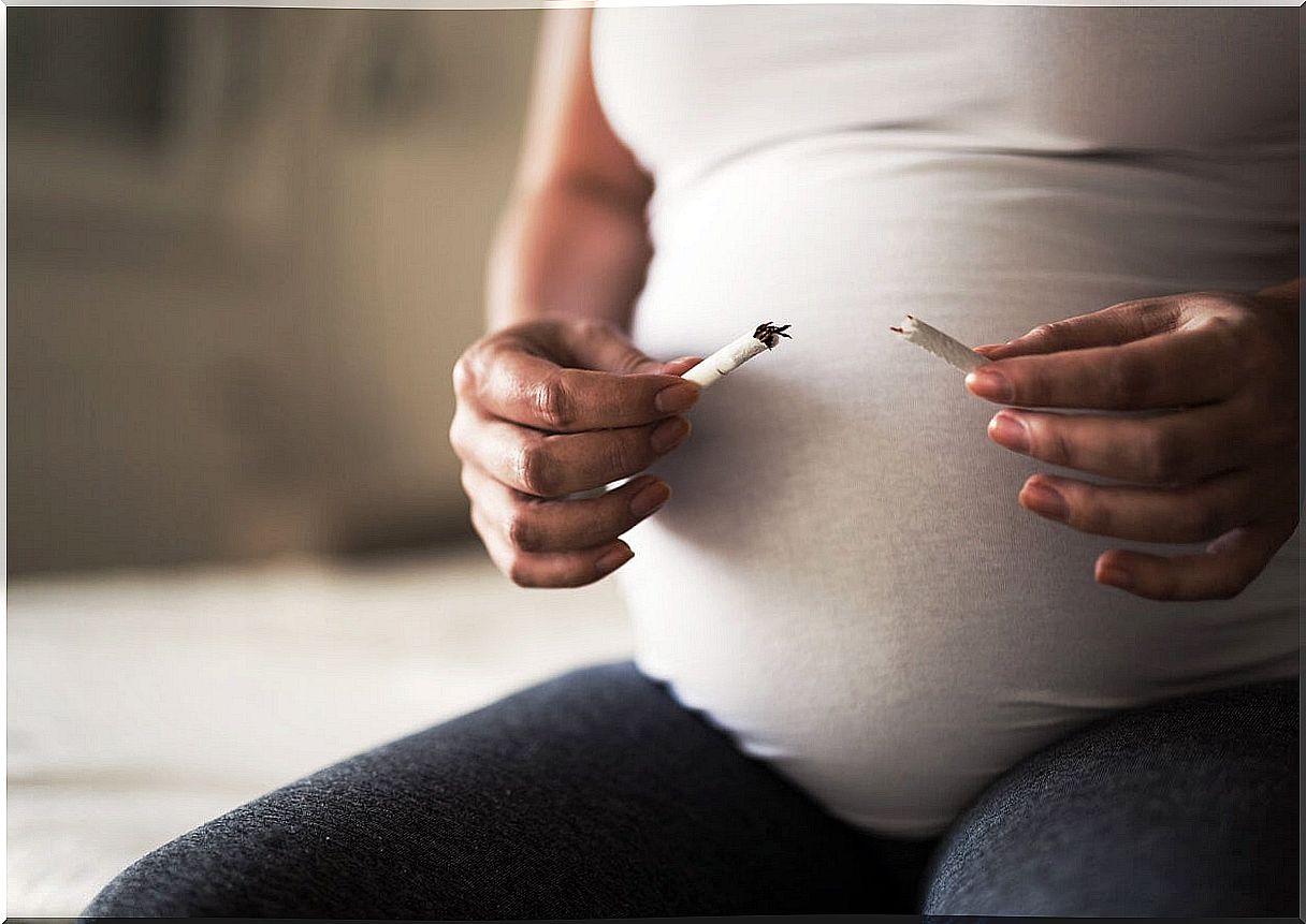 Pregnant woman breaking a cigarette.