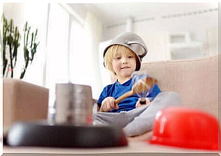 A child playing musical instruments in the kitchen. 