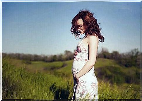 A pregnant woman in a field in summer