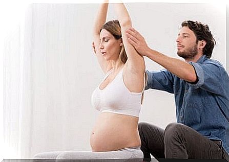 A man helping his wife to practice pre-childbirth exercises