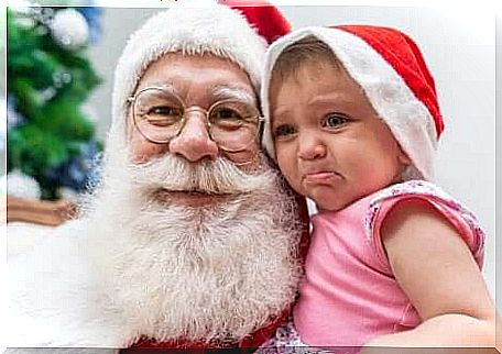 A crying baby in the arms of Santa Claus. 