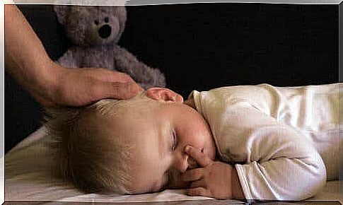 A baby sleeping with his mother caressing him.