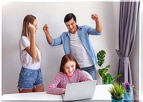 girl and her parents in front of a computer