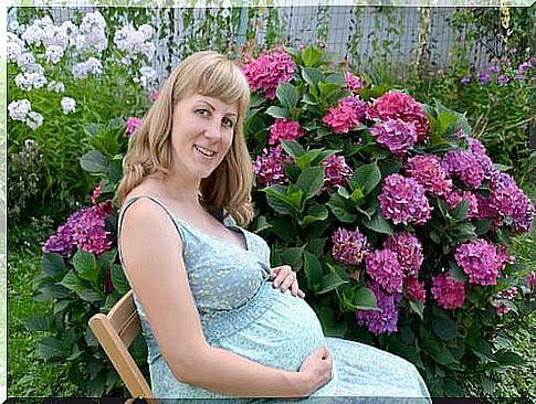 A pregnant woman is sitting in her garden