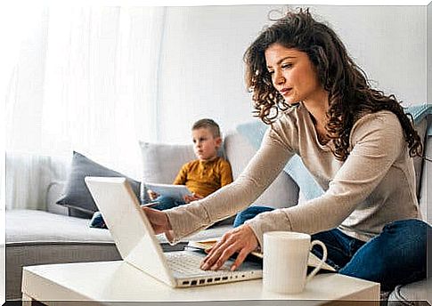 A mother on her computer and her son in front of the television.