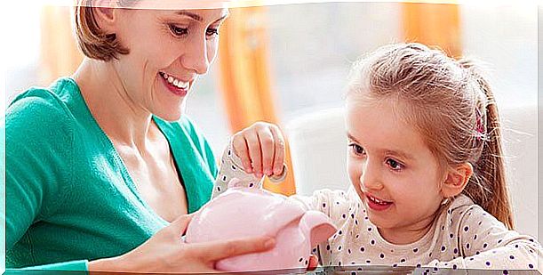 A young girl putting coins in her piggy bank. 